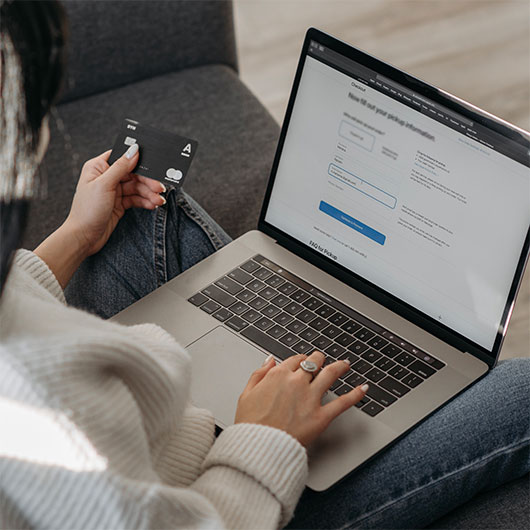 Une personne paie en ligne avec sa carte bancaire devant un ordinateur portable